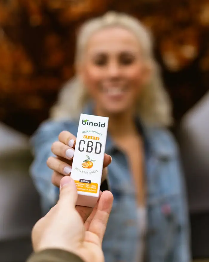 A woman holds a box of water soluble CBD drops with a focus on the product.